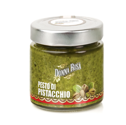 A small glass jar of green pesto sauce with a silver metal lid and a colorful label, centered on a plain white background.